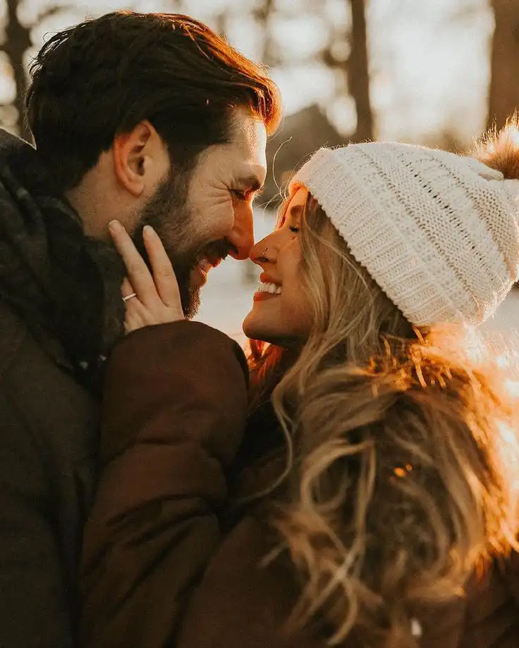 _ 9 A couple enjoying a cozy winter moment, sharing a loving gaze under the warm sunset, wrapped in coats and a knitted beanie. | Sky Rye Design A couple enjoying a cozy winter moment, sharing a loving gaze under the warm sunset, wrapped in coats and a knitted beanie.