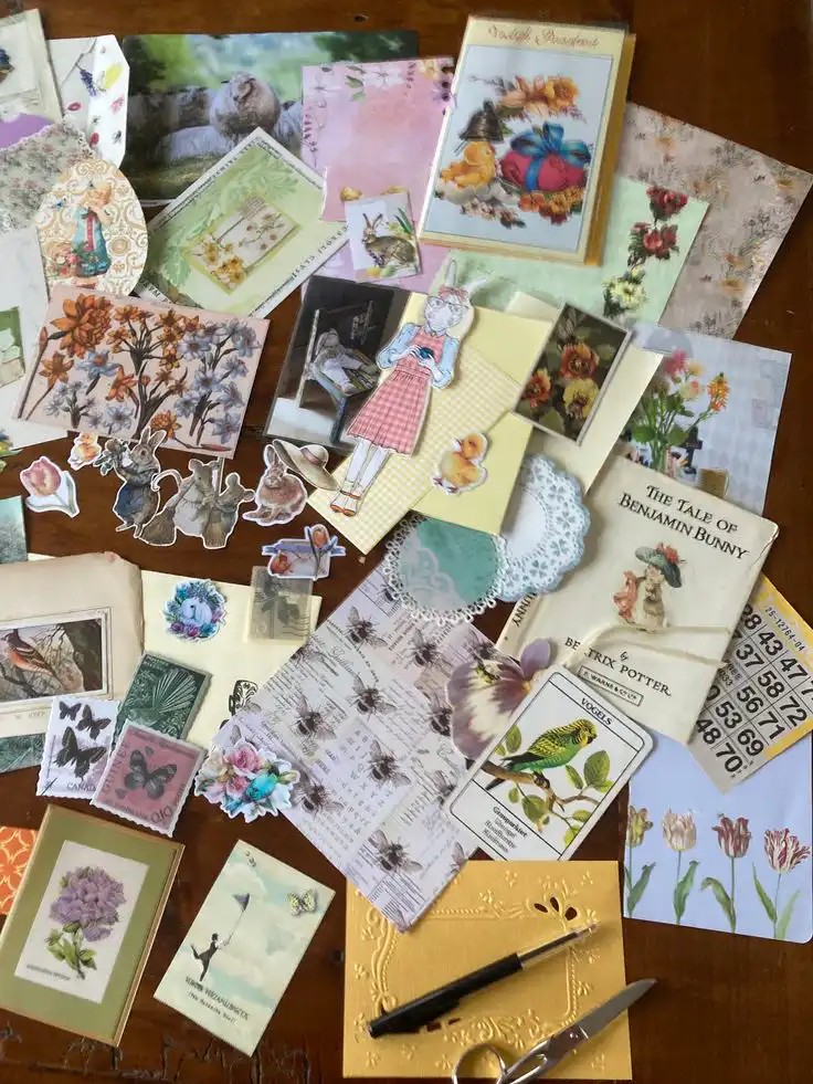 Vintage-themed scrapbook papers and cutouts, featuring floral, animal, and whimsical designs, scattered on a wooden table.