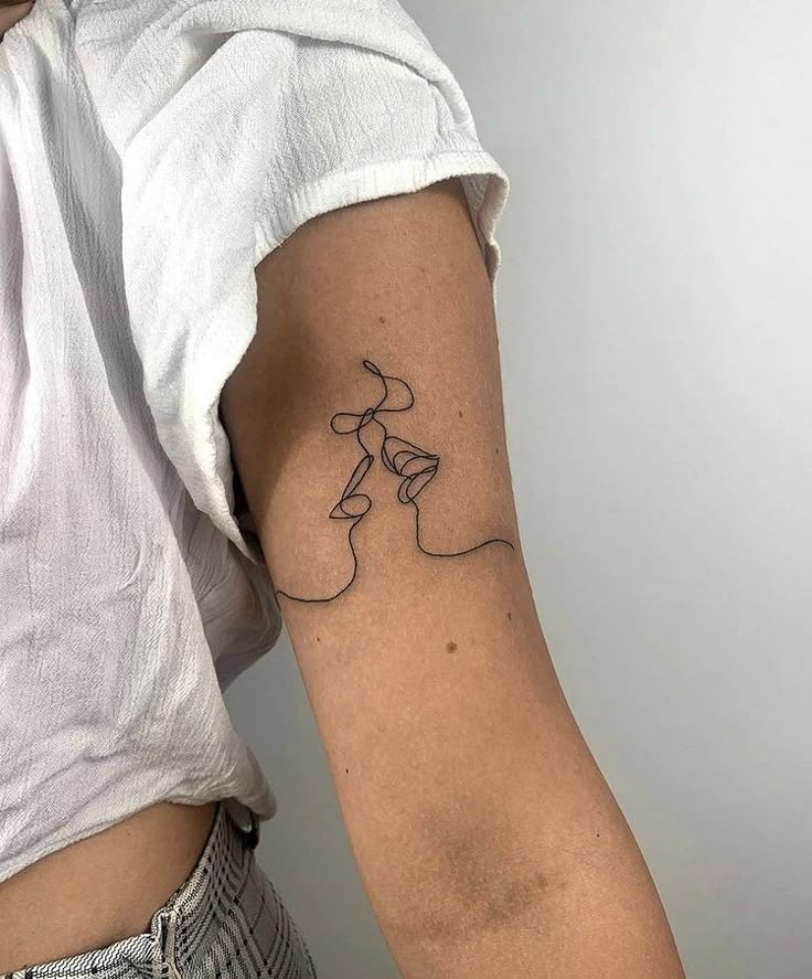98005692-3625-41f2-82a1-bc406a1be464 Minimalist one-line tattoo of two faces on a person's upper arm, wearing a white shirt. | Sky Rye Design Minimalist one-line tattoo of two faces on a person's upper arm, wearing a white shirt.