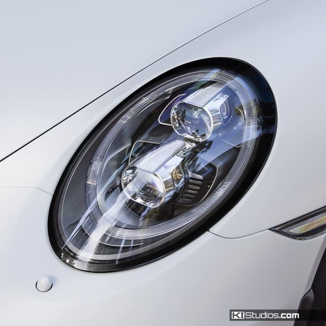 Close-up of a sleek car headlight on a white vehicle, showcasing the intricate design and modern styling.