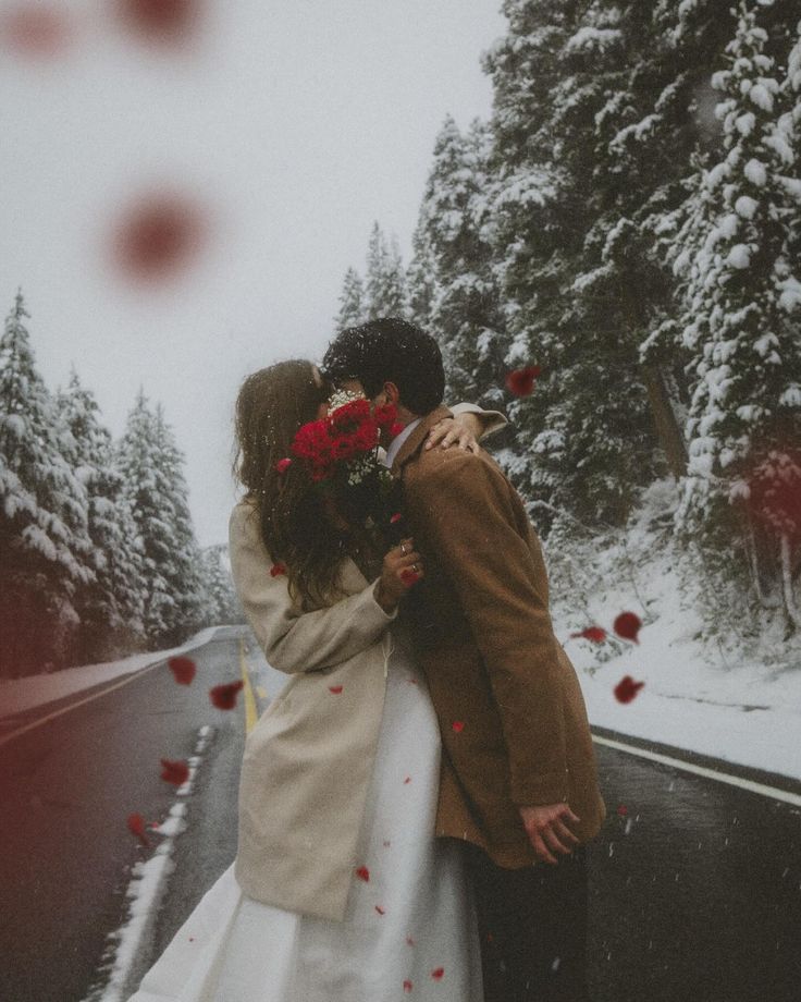 A Winter Elopement ❄️ __I had some idea it was snowing but I had no idea it was like snowing snowing_ So for this photoshoot I wore socks and sandals cuz I ✨ plan things really well ahead of time ✨ Romantic couple kissing on a snowy road, surrounded by rose petals and winter trees, embracing in a serene winter wonderland. | Sky Rye Design Romantic couple kissing on a snowy road, surrounded by rose petals and winter trees, embracing in a serene winter wonderland.