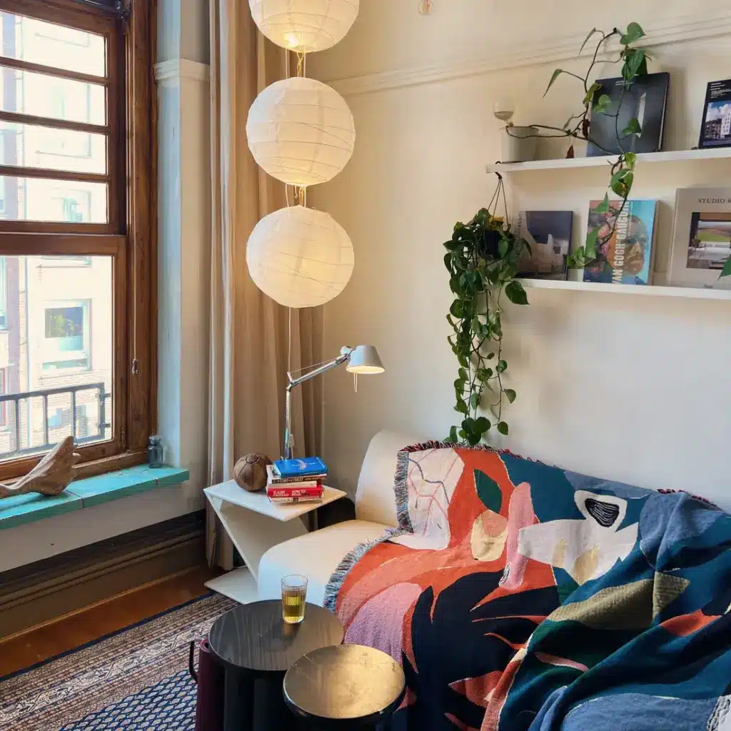 Atelier_103_Slow_Down_Studio_11_ea04e098-f45b-4582-bd17-f185c430ceb9 Cozy living room with colorful blanket, white paper lanterns, and lush green plants, creating a warm, inviting atmosphere by the window. | Sky Rye Design Cozy living room with colorful blanket, white paper lanterns, and lush green plants, creating a warm, inviting atmosphere by the window.