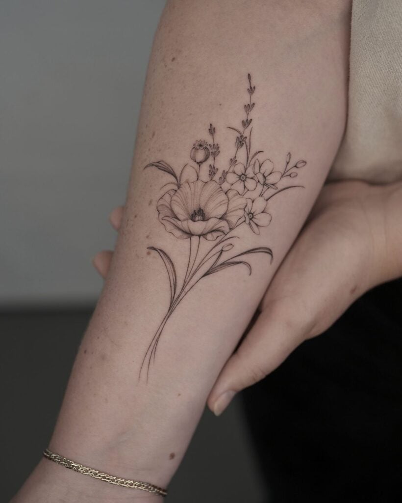Delicate floral tattoo on forearm, showcasing intricate flower design in black ink for minimalist body art inspiration.