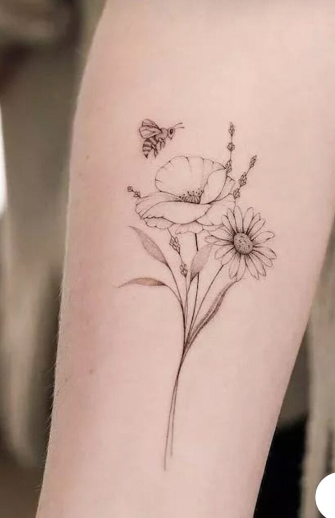 Delicate flower and bee tattoo on forearm, showcasing fine line art with poppy and daisy design.