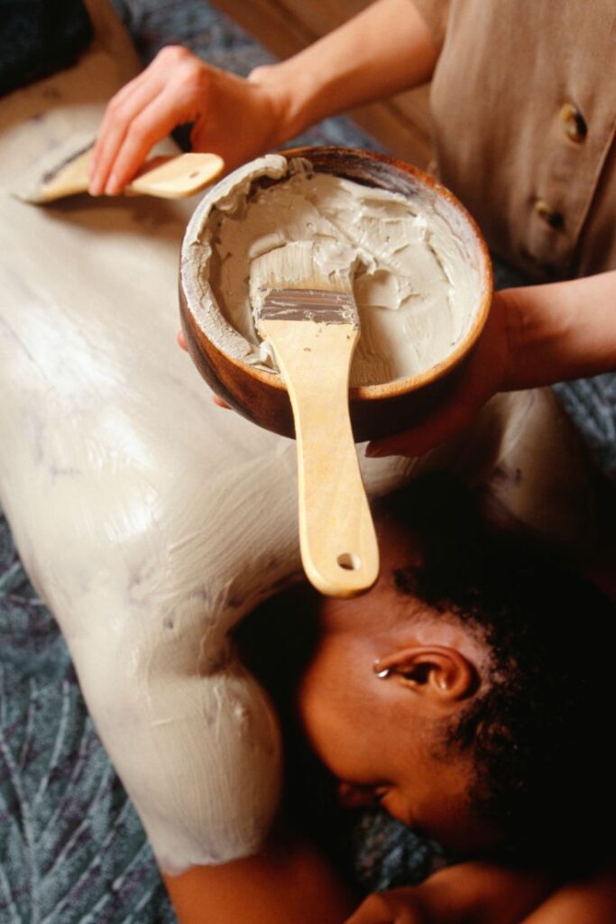 Body Wrap Person receiving a relaxing mud body wrap treatment at a spa, enhancing skin and wellness relaxation with natural clay. | Sky Rye Design Person receiving a relaxing mud body wrap treatment at a spa, enhancing skin and wellness relaxation with natural clay.