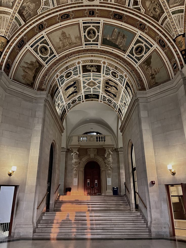 Carnegie Mellon University College of Fine Art 1 Ornate architectural hall with intricate mural ceiling, illuminated stairs, and elegant stone details in a grand historic building. | Sky Rye Design Ornate architectural hall with intricate mural ceiling, illuminated stairs, and elegant stone details in a grand historic building.