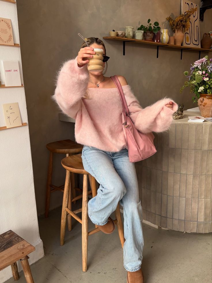 Category_ coffee date 🫖☕️🎀__coffeedate outfitoftoday pinterestinspo girlyaesthetic girlyoutfits fashionstyle Stylish woman in a pink off-the-shoulder sweater and jeans, holding iced coffee, sitting at a cozy cafe with floral decor. | Sky Rye Design Stylish woman in a pink off-the-shoulder sweater and jeans, holding iced coffee, sitting at a cozy cafe with floral decor.
