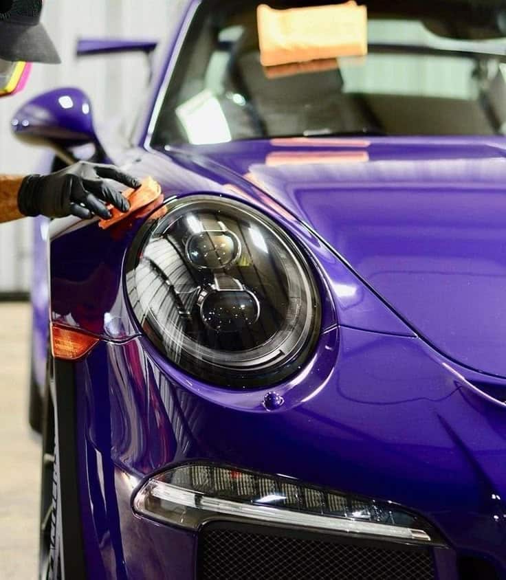 Ceramic coating Close-up of a person polishing the headlight of a shiny purple sports car, highlighting sleek design and car detailing. | Sky Rye Design Close-up of a person polishing the headlight of a shiny purple sports car, highlighting sleek design and car detailing.