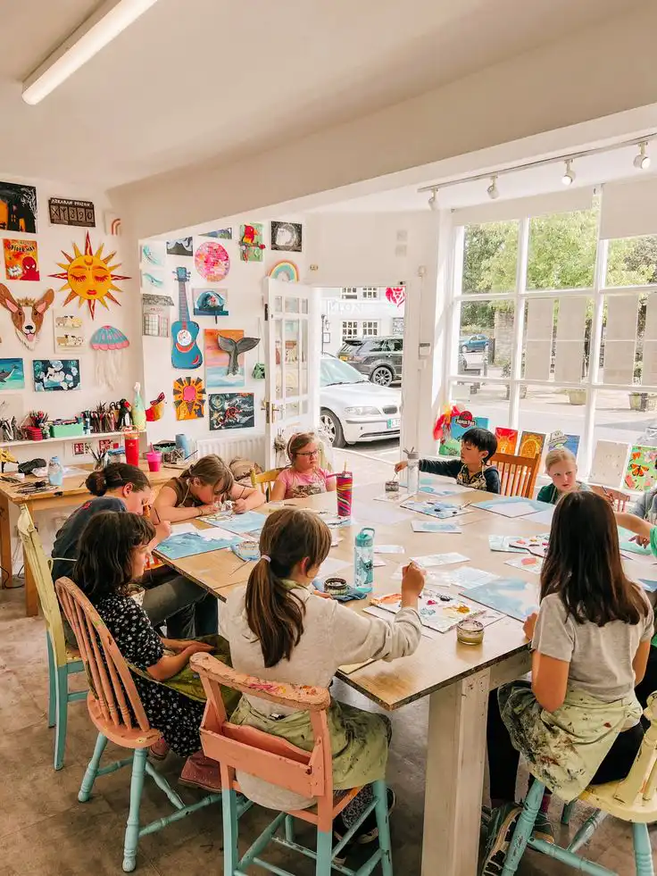 Childrens Art Lessons - Jessies Art Shed Children engaged in colorful art projects in a bright, creative classroom filled with paintings and natural light. | Sky Rye Design Children engaged in colorful art projects in a bright, creative classroom filled with paintings and natural light.