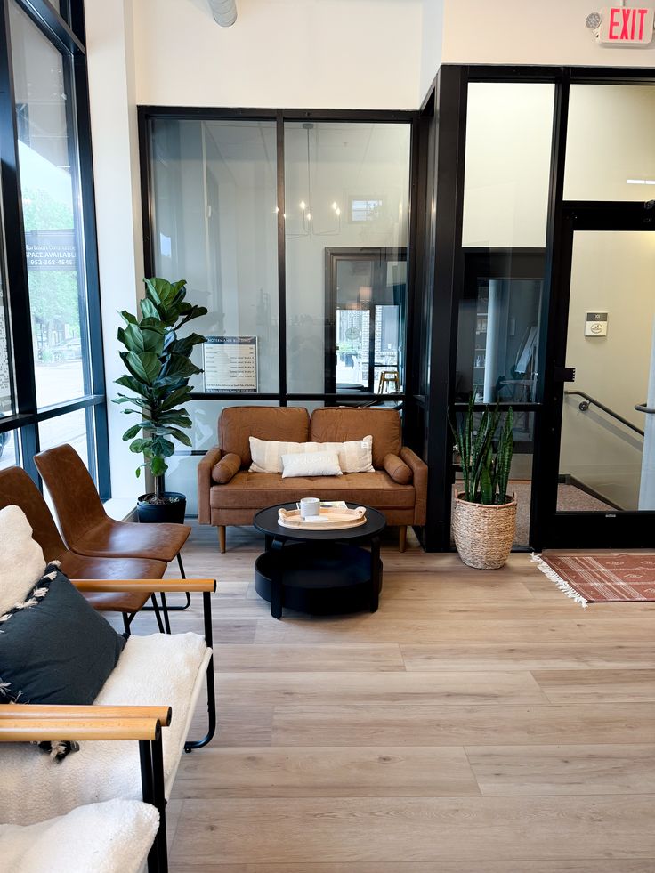 Cozy Waiting Room Lobby Cozy modern office lounge with seating, plants, and warm decor. Sunlight through windows creates an inviting atmosphere for relaxation. | Sky Rye Design Cozy modern office lounge with seating, plants, and warm decor. Sunlight through windows creates an inviting atmosphere for relaxation.