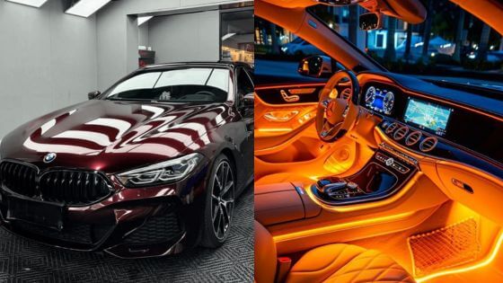 A sleek burgundy BMW parked indoors alongside a luxury car interior glowing with vibrant orange ambient lighting.