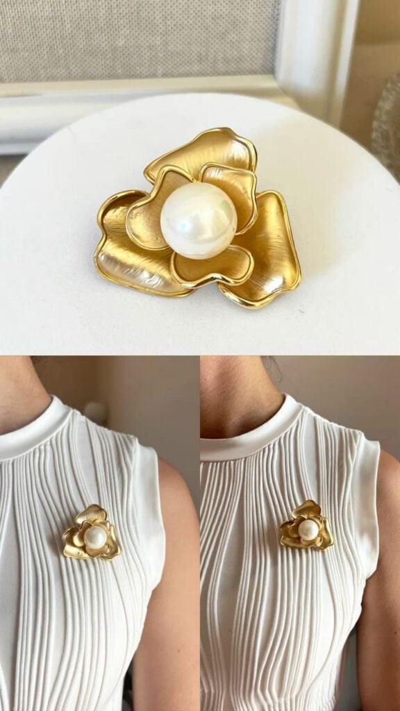 Designers flower brooch 💫 Elegant gold flower brooch with pearl center on white pleated dress, showcasing timeless fashion accessories and sophisticated style. | Sky Rye Design Elegant gold flower brooch with pearl center on white pleated dress, showcasing timeless fashion accessories and sophisticated style.