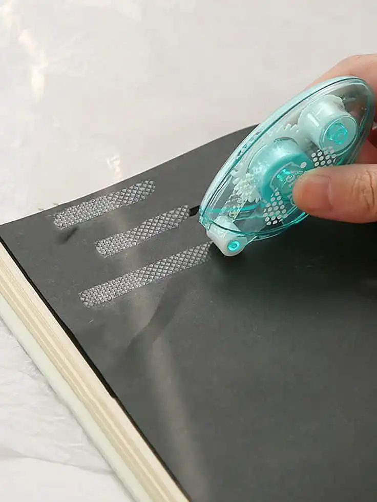 Using a correction tape on black paper for clean, precise lines. Ideal for crafting, scrapbooking, and error-free projects.