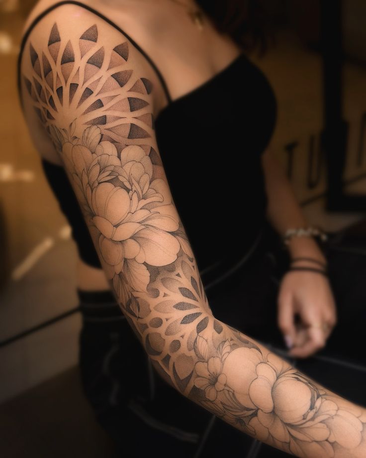 Geometric and floral sleeve Done in 3 sessions Intricate full sleeve tattoo featuring floral and geometric designs on a woman's arm, showcasing detailed black and gray artistry. | Sky Rye Design Intricate full sleeve tattoo featuring floral and geometric designs on a woman's arm, showcasing detailed black and gray artistry.