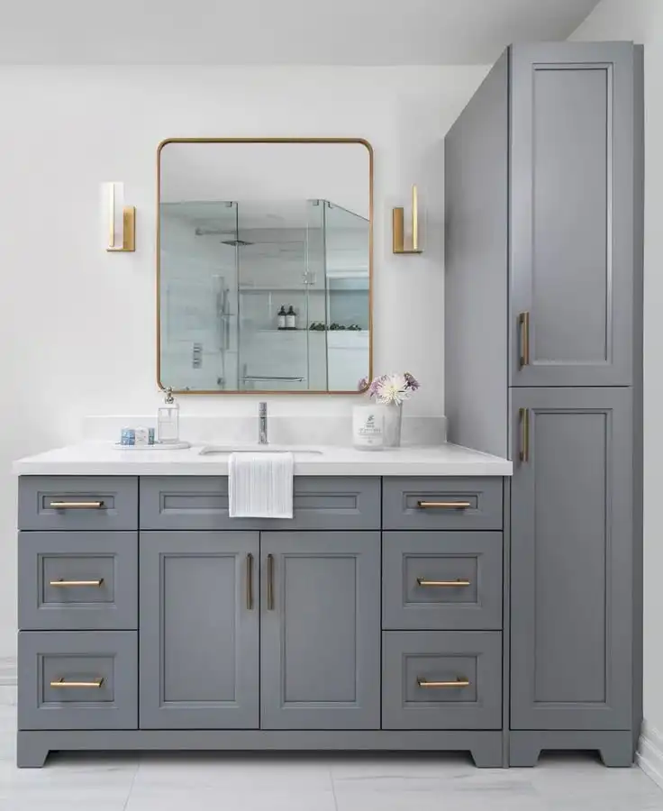 Modern bathroom with gray vanity, gold hardware, large mirror, and elegant lighting fixtures. Minimalist design with fresh