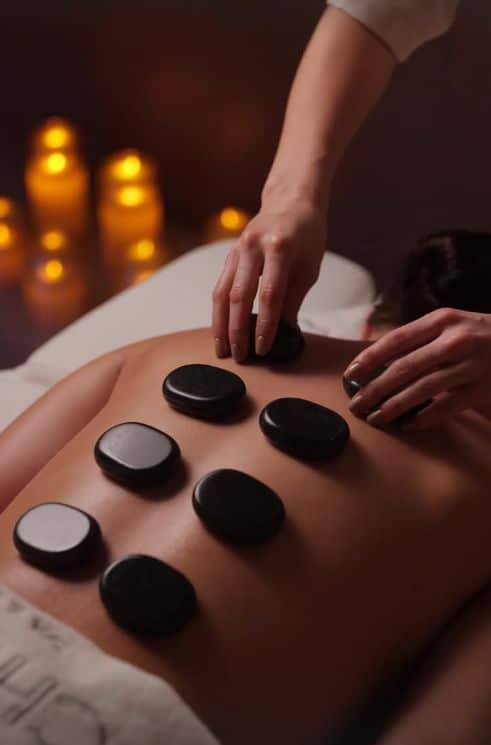 Hot stone spa in Abu Dhabi Person receiving hot stone massage therapy in a tranquil spa setting with soothing candlelight. | Sky Rye Design Person receiving hot stone massage therapy in a tranquil spa setting with soothing candlelight.