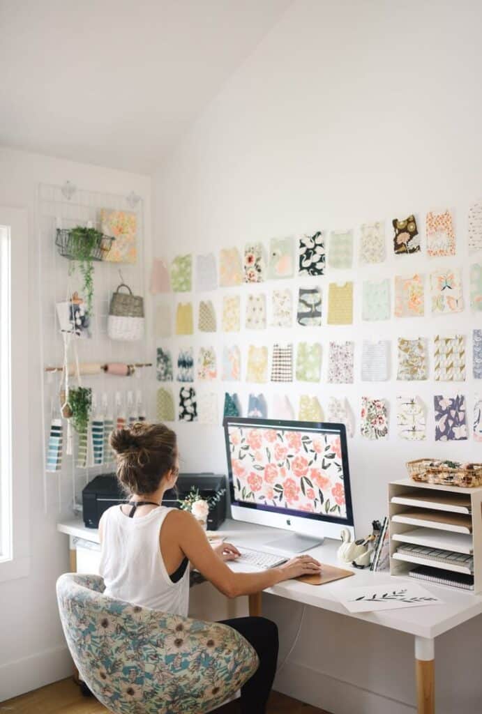 How to follow your dreams by googling _ Designer working in a creative studio, surrounded by floral patterns and fabric samples on walls, using a desktop computer. | Sky Rye Design Designer working in a creative studio, surrounded by floral patterns and fabric samples on walls, using a desktop computer.