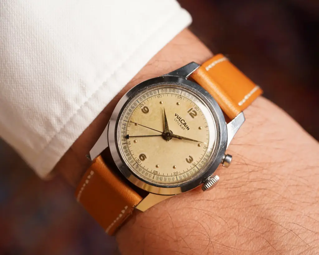 Vintage Vulcain wristwatch with a tan leather strap and beige dial on a person's wrist, perfect for classic style enthusiasts.