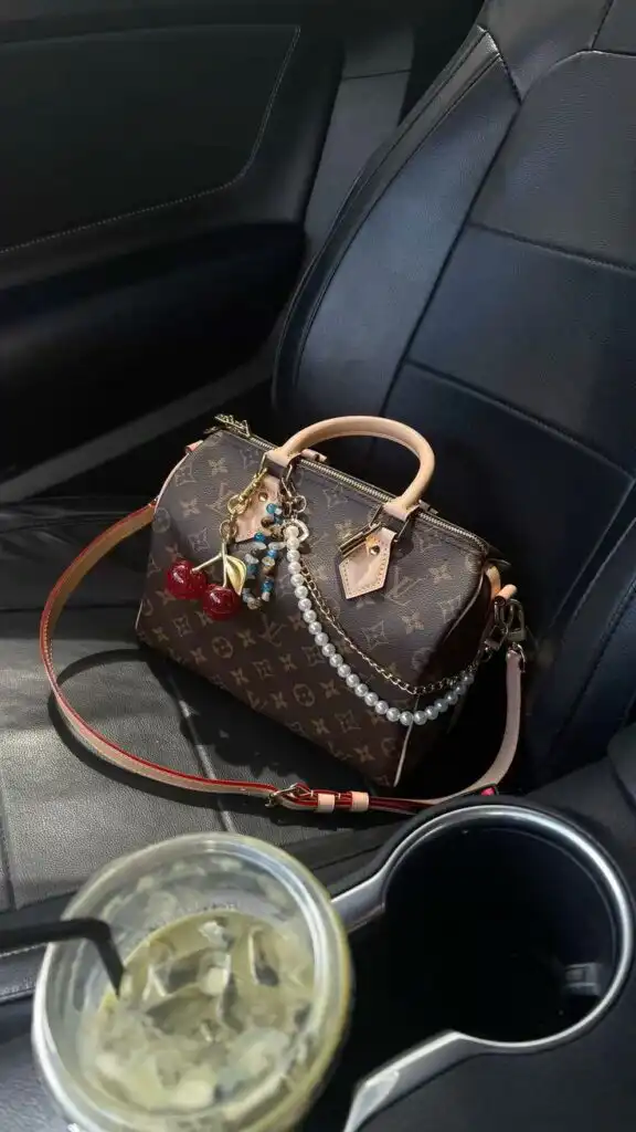 Luxury handbag on car seat with pearl and charm accessories; iced drink in cup holder adds modern style contrast.