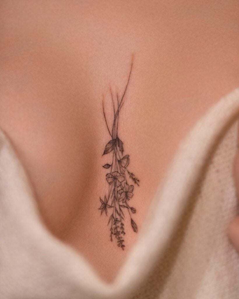 Delicate floral tattoo on a woman's chest, showcasing intricate lines and blooming flowers.