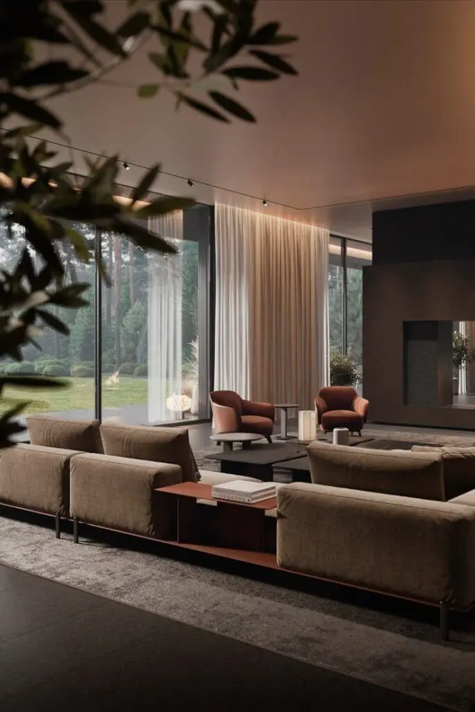 Modern living room with large windows, beige sofas, and cozy armchairs overlooking a lush garden, framed by elegant curtains.