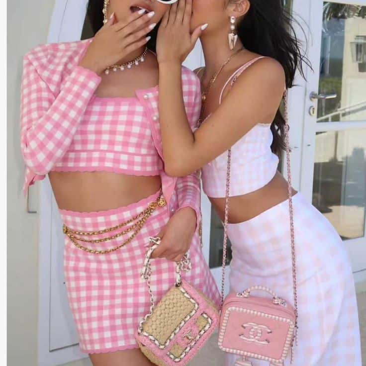 Loveshackfancy Sweaters _ Nwt Loveshackfancy Bridgette Checkered Knit Cardigan Xsmall Pink Pearl Plaid _ Color_ Pink_White _ Size_ Xs Two stylish women in pink gingham outfits share a secret, each holding a trendy handbag and wearing chic accessories, standing outdoors. | Sky Rye Design Two stylish women in pink gingham outfits share a secret, each holding a trendy handbag and wearing chic accessories, standing outdoors.