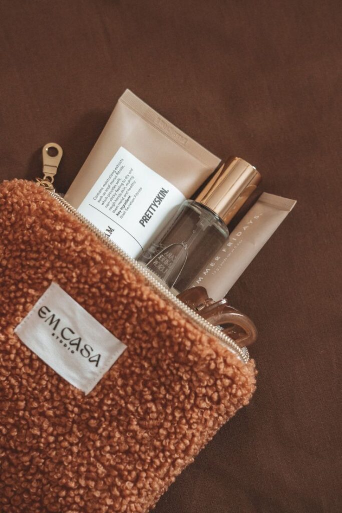 Cozy brown pouch containing skincare products and a glass bottle, ideal for travel and beauty routines.
