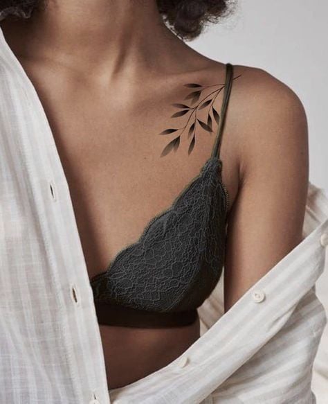 Woman in lace black bralette with leaf tattoo on shoulder, wearing an open white shirt. Fashion, style, and tattoo art concept.
