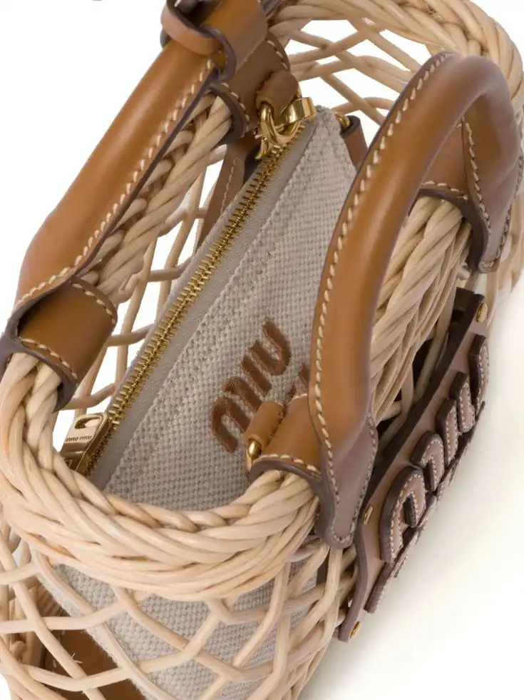 Close-up of a stylish woven handbag with leather accents and a zipped canvas pouch inside, featuring elegant branding details.