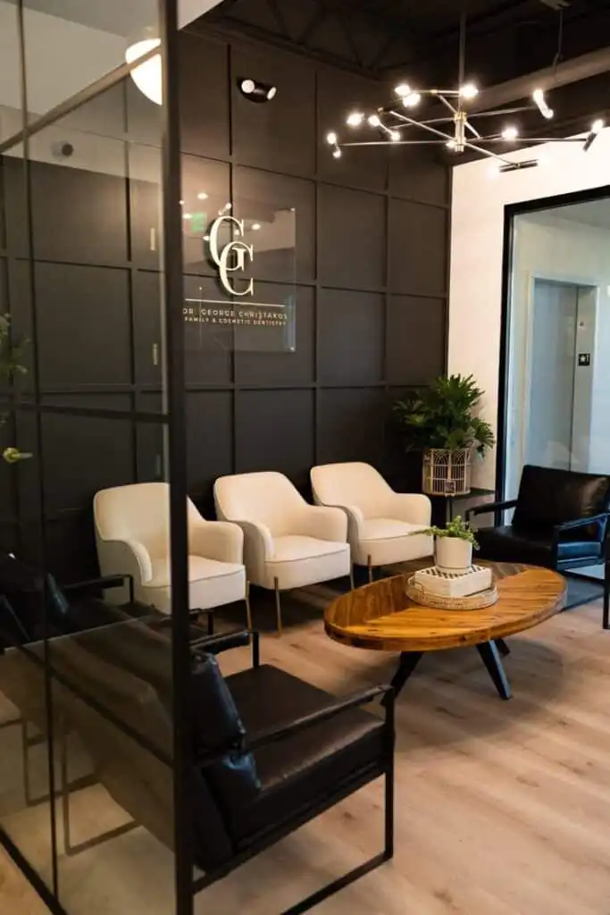 Modern dental office waiting area with stylish chairs, wooden table, and decorative lighting, creating a welcoming atmosphere.