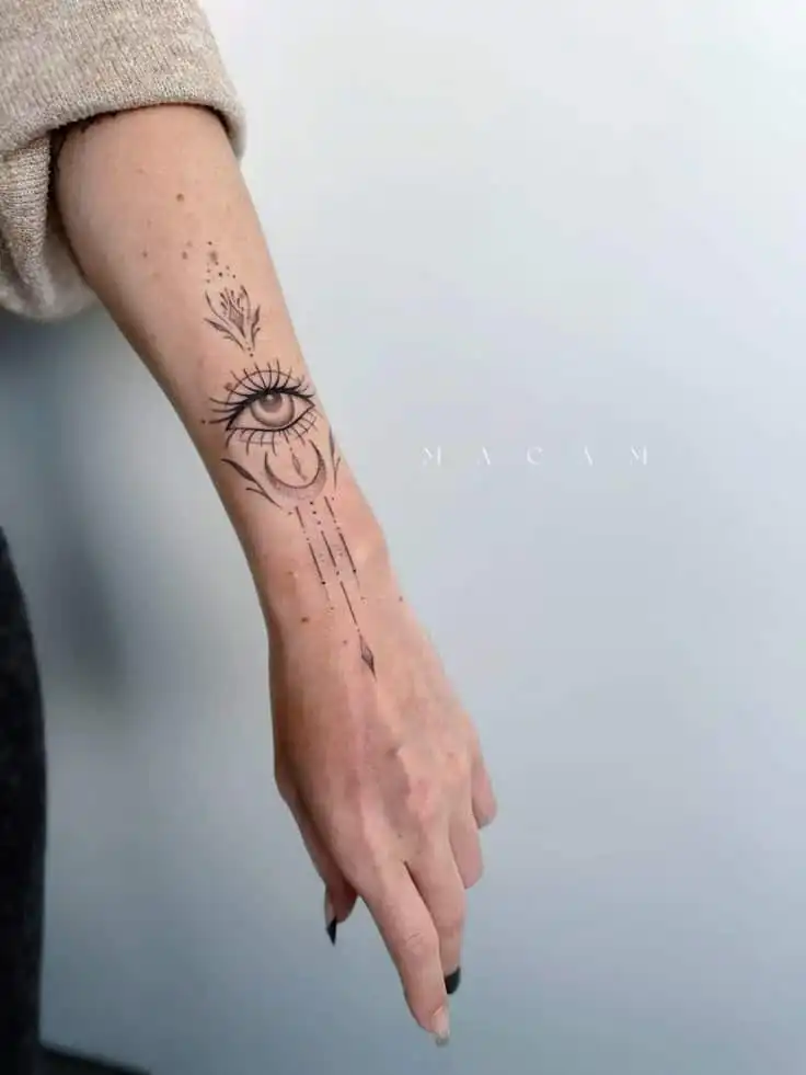 Mystical Eye and Moon Dotwork Tattoo Artistic forearm tattoo featuring a detailed eye with ornamental designs and lines on a person’s arm against a light background. | Sky Rye Design Artistic forearm tattoo featuring a detailed eye with ornamental designs and lines on a person’s arm against a light background.