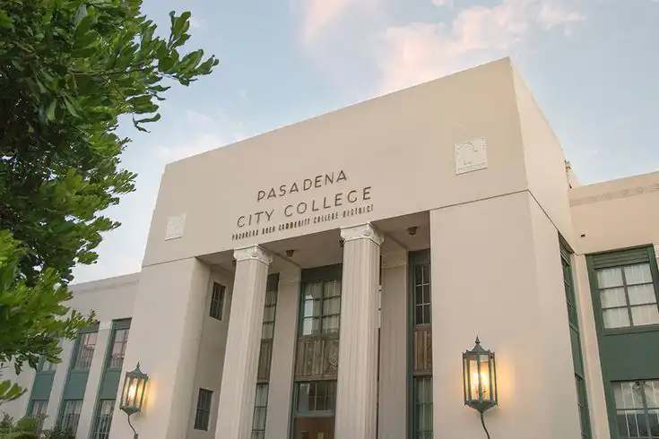 Modern facade of Pasadena City College building with white columns, lanterns, and clear blue sky.