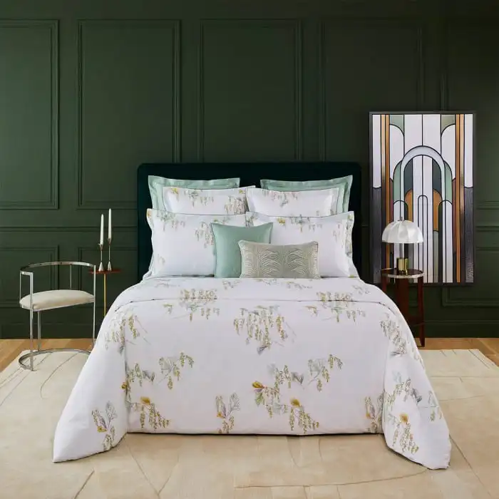 Luxurious bedroom with a floral-patterned duvet, green accent pillows, dark green wall, and modern decor for a stylish and cozy ambiance.