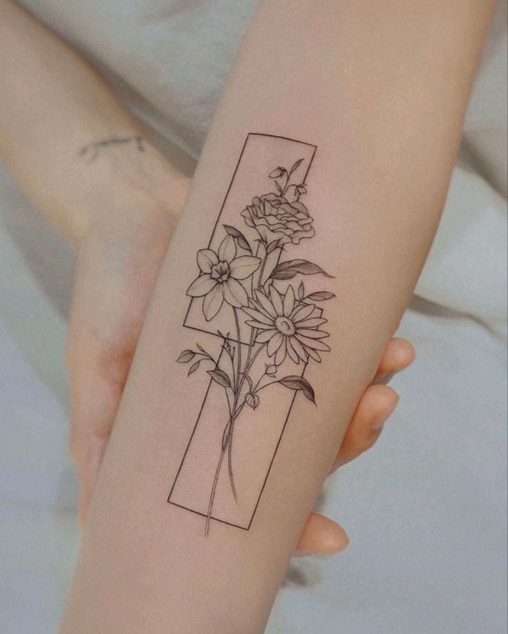 Minimalist floral tattoo on forearm, featuring delicate flowers framed in a rectangle design. Perfect for nature-inspired ink enthusiasts.