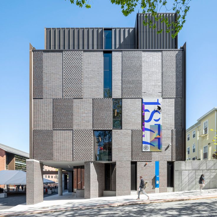 Rhode Island School of Design RISD Gretel Modern architectural building with patterned facade and colorful vertical banner, set against a clear blue sky. | Sky Rye Design Modern architectural building with patterned facade and colorful vertical banner, set against a clear blue sky.