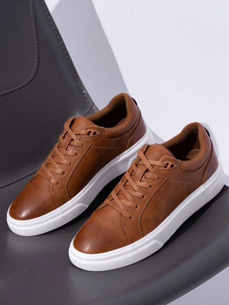Brown leather sneakers with white soles on a gray chair, showcasing casual style and comfort for everyday wear.