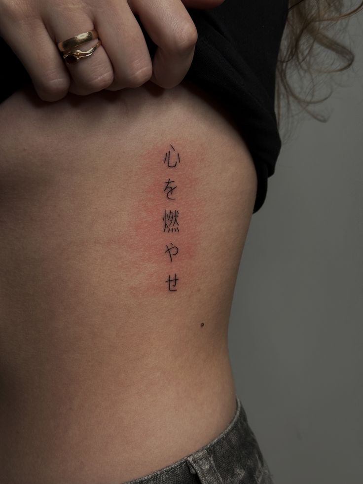 Set Your Heart Ablaze Japanese Fine Line Tattoo Minimalist Japanese kanji tattoo on a person's ribcage, showcasing elegant script and subtle shading against light skin. | Sky Rye Design Minimalist Japanese kanji tattoo on a person's ribcage, showcasing elegant script and subtle shading against light skin.