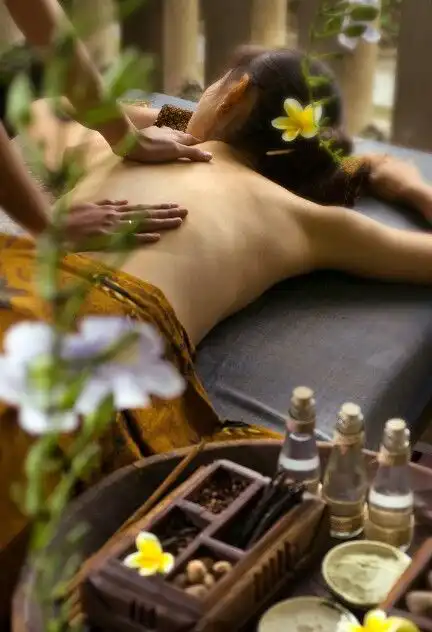Woman receiving a relaxing back massage in a spa setting, surrounded by nature-inspired decor, aromatic oils, and fresh flowers.