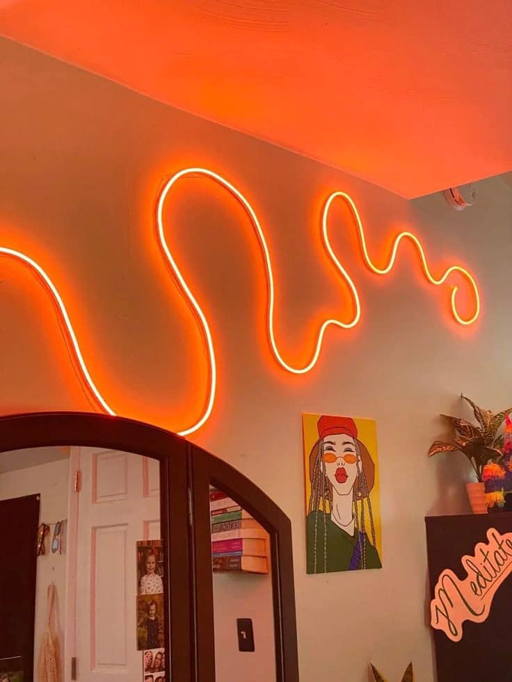 Squiggle Neon LED Lights Dreamcolor Rope for Decor Vibrant room decor with orange neon light, colorful artwork, books, and houseplants, creating a stylish and cozy atmosphere. | Sky Rye Design Vibrant room decor with orange neon light, colorful artwork, books, and houseplants, creating a stylish and cozy atmosphere.