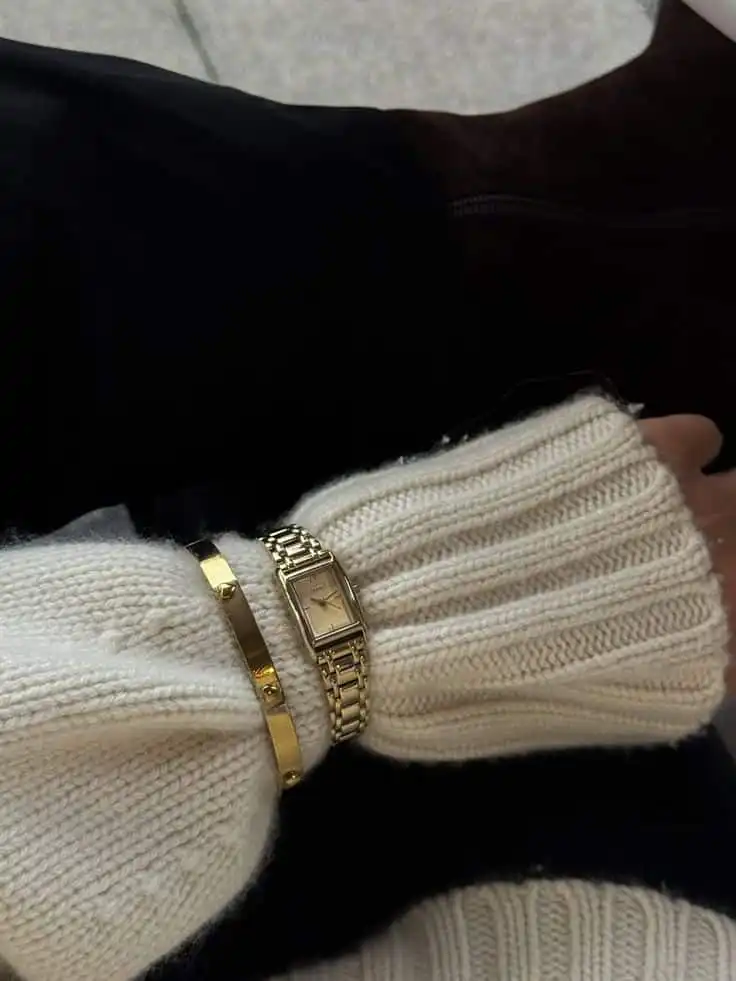 Cozy white sweater with a gold watch and bracelet on wrist, stylish and elegant, perfect for a chic winter fashion look.