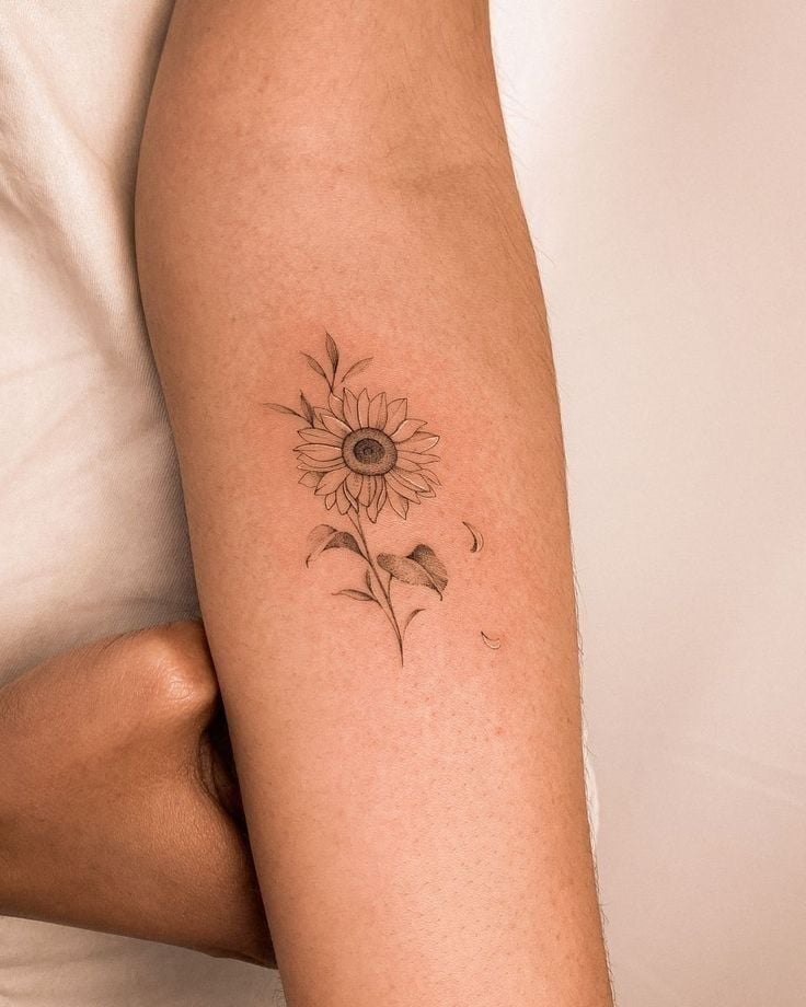 Minimalist sunflower tattoo on forearm, showcasing delicate petals and leaves for a unique floral design. Ideal for tattoo inspiration.