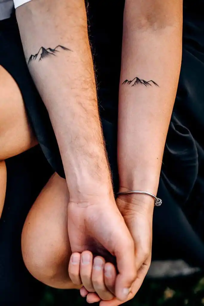 Tattoo Ideas Couple holding hands with matching mountain tattoos on forearms, symbolizing unity and adventure. | Sky Rye Design Couple holding hands with matching mountain tattoos on forearms, symbolizing unity and adventure.