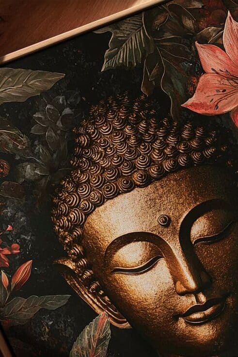 Buddha artwork with serene face, surrounded by vibrant flowers and lush leaves, exuding peace and tranquility.