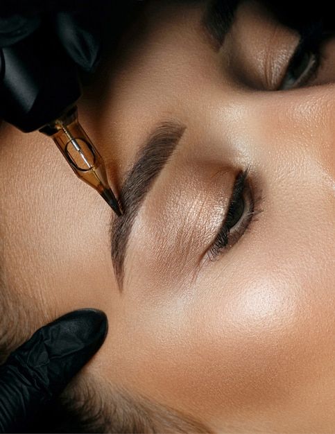 Top view of a beautician hand doing eyebrow permanent makeup on woman face _ Premium Photo Microblading close-up: beautician's gloved hand applying precise strokes to eyebrows, enhancing shape and definition for a natural look. | Sky Rye Design Microblading close-up: beautician's gloved hand applying precise strokes to eyebrows, enhancing shape and definition for a natural look.