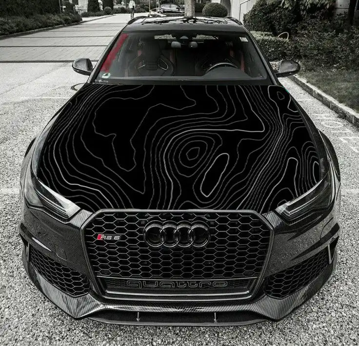 Sleek black Audi RS6 with unique topographic design on hood, parked outdoors. Perfect blend of luxury and artistic style.