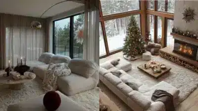 Cozy winter living room with large windows, a Christmas tree, candles, and a plush sofa, showcasing a warm and inviting holiday atmosphere.