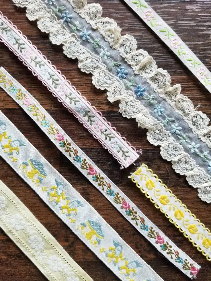 Assorted decorative ribbons with floral and lace patterns on a wooden surface, ideal for crafting and sewing projects.