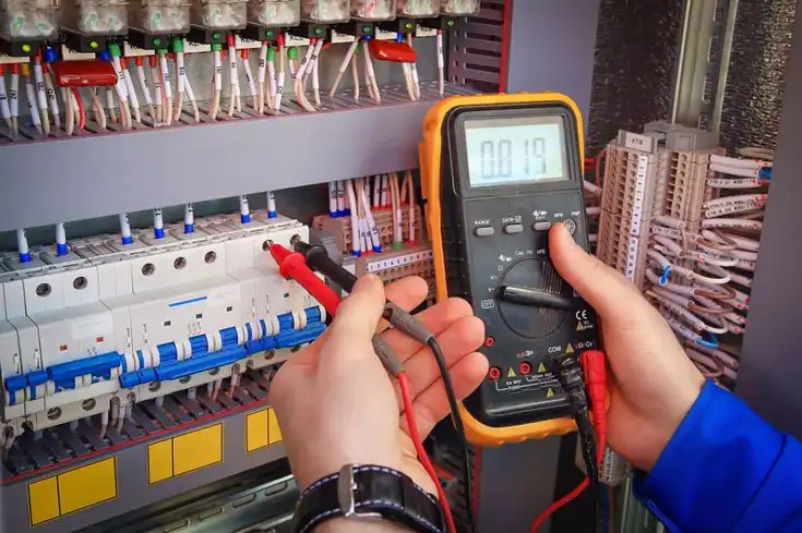 Technician using a digital multimeter to test electrical panel connections, ensuring safe and efficient circuit