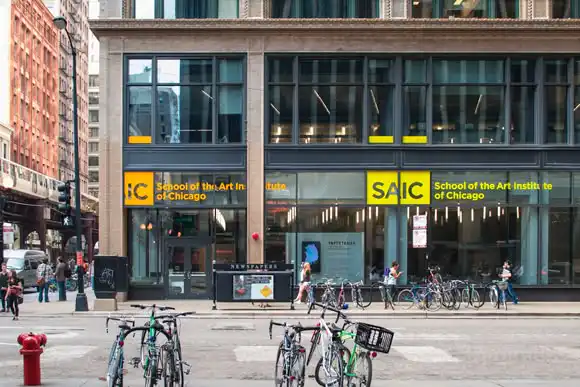 Front view of the School of the Art Institute of Chicago building with bicycles parked outside and pedestrians walking by.