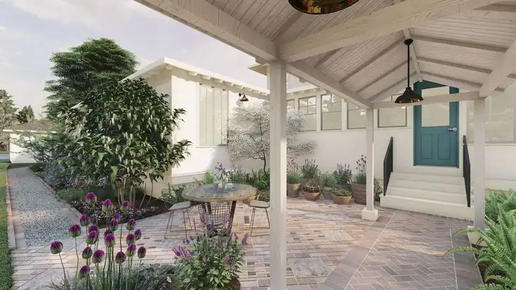Charming backyard patio with table, plants, and white pergola, leading to a house with blue door. Peaceful outdoor garden space.